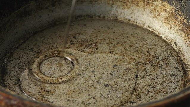 Vegetable oil is poured into a cast-iron skillet heated over a fire