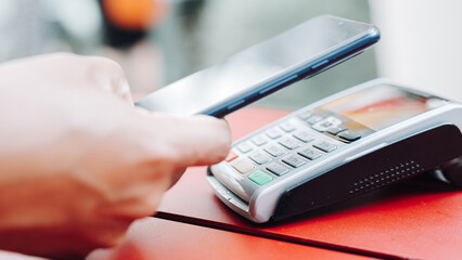Hands holding a mobile device near a payment terminal, highlighting the convenience of contactless payments.