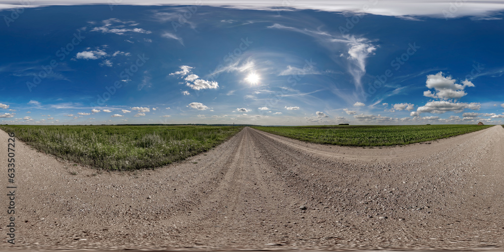 Wall mural 360 hdri panorama on wet gravel road with marks from car or tractor tires with clouds on blue sky in