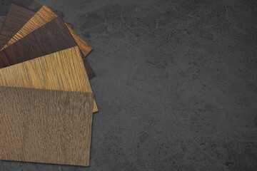 top view, stacked of wooden laminated flooring samples for interior renovation placed on dark grey...