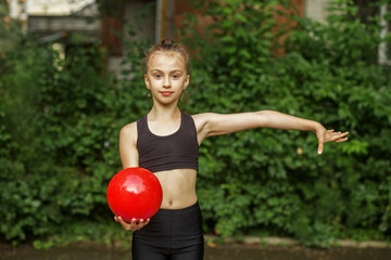 Rhythmic gymnastics. Preteen child gymnast performs an exercise with ball on sport mat.