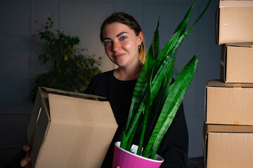 Happy woman moving in carrying cartons boxes with red paper house and key. Young girl arranging interior and unpacking at new apartment home.