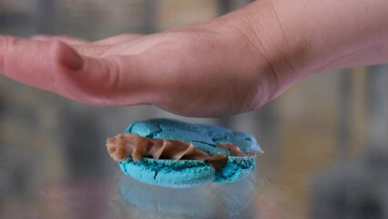 flatten with the palm of blue lavender macaroons macaroons dorblue with cream on a glass press with a female hand close-up rejection of sweet weight loss no sugar against desserts. sugar free diet