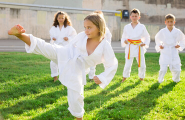Adorable european preteen girl practicing karate on sunny day in park