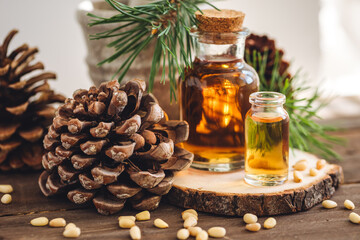 Organic essential oil, pine nuts, cedar cone on rustic wooden dark background. Concept of natural...