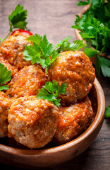 Pork and beef meatballs in tomato sauce with parsley in wooden bowl on rustic wood kitchen table. Delicious home cooking. Top view