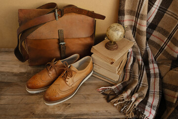 closeup old things, stack of vintage books, globe, shoes, leather military satchel on table,...