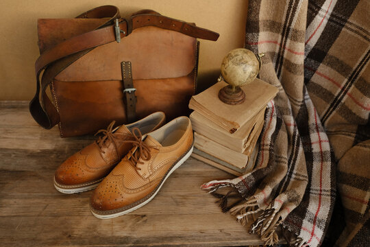 closeup old things, stack of vintage books, globe, shoes, leather military satchel on table, checkered grandmother's plaid, concept of family tree, home archive, genealogy, memory of ancestors