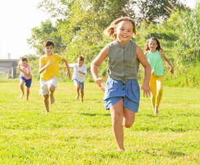 Naklejka na ściany i meble Happy active children running together on green grass in park