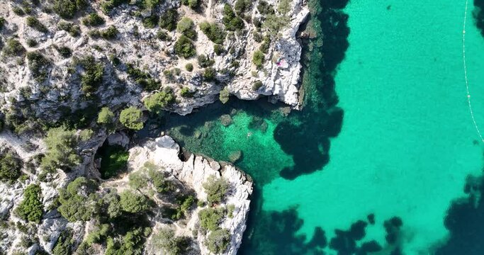Small notch in the cliffs at the Calanque national park with people swimming there in the National Park Calanques. between Marseille and the town of Cassis. rugged rocky mountains