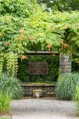 Landscape architecture featuring pergola and brass water feature and perennials