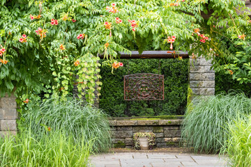 Landscape architecture featuring pergola and brass water feature and perennials