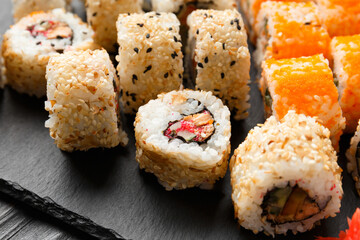 close up of sushi rolls on black tray