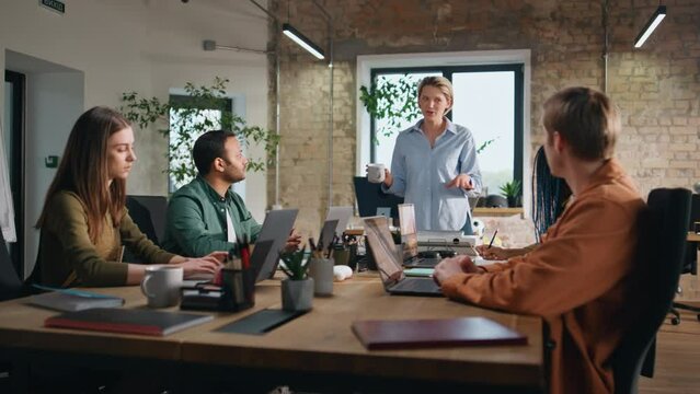 Multiethnic group coworkers discussing work in conference room. Woman explaining