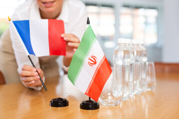 Little flag of Iran on table with bottles of water and flag of France put next to it by positive...