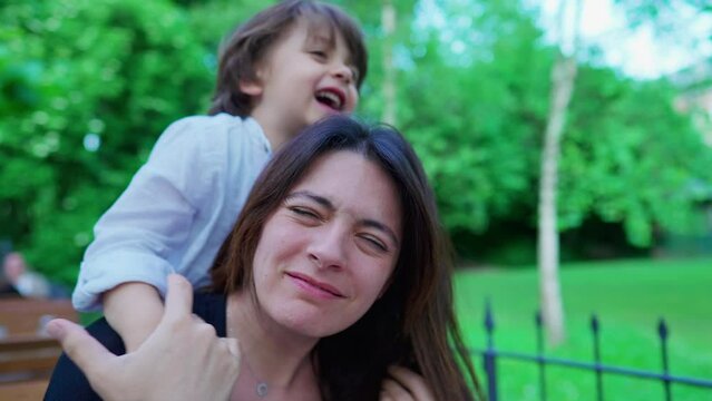 Careless small boy choking mom while playing. Kid not knowing play limits, upset mother, real life