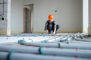 Woman worker takes measurements during the installation of a warm floor. Warm floor heating system