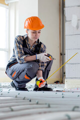 Woman worker takes measurements during the installation of a warm floor. Warm floor heating system