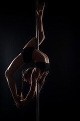 Pole dance. Sexy ballerina in black underwear stretching on black background. Concept of ballet...