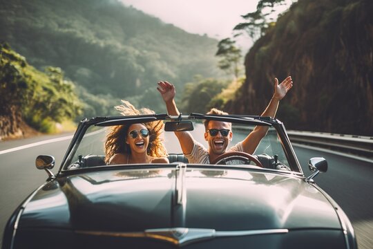 Happy Couple Driving On Country Road With Raised Hands.