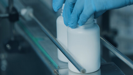 The process of placing caps on white plastic tubes. The Tubes Move Along a Conveyor Belt In a...