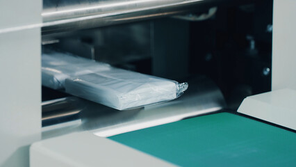 Plastic wrapping machine on production line. Cutting off the polyethylene packaging. Drugs production, pharmacist working, pharmaceutical manufacturing, pharmaceutical industry concept