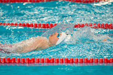 Swimmer boy swims backstroke swimming style in the pool - 633533031