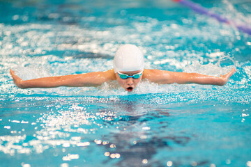 Swimmer boy swims butterfly swimming style in the pool