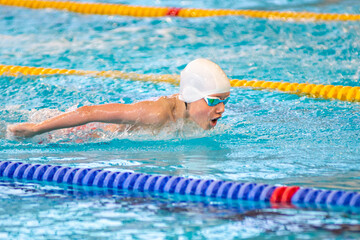 Swimmer boy swims butterfly swimming style in the pool - 633533035