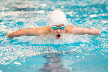 Fototapeta na wymiar Swimmer boy swims butterfly swimming style in the pool