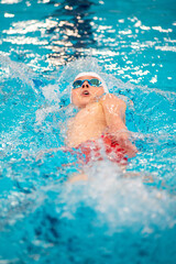 Swimmer boy swims backstroke swimming style in the pool - 633533038