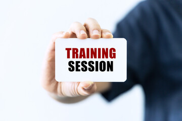 Training session text on blank business card being held by a woman's hand with blurred background....