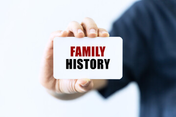 Family history text on blank business card being held by a woman's hand with blurred background. Business concept about family history.