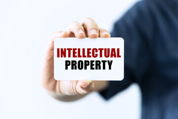 Intellectual property text on blank business card being held by a woman's hand with blurred background. Business concept about intellectual property.