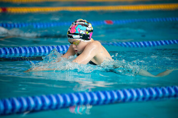 Swimmer child swims breaststroke swimming style in the pool - 633533066