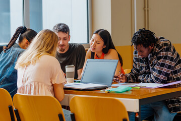diverse and multiracial group of young students working and studying together on a project using their laptops and class notes. academic brainstorming. back to school.