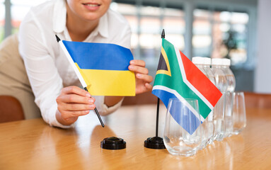 Little flag of South Africa on table with bottles of water and flag of Ukraine put next to it by...