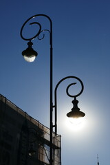 Fototapeta na wymiar Street lamp with the sun exactly behind the lightbulb in an urban environment