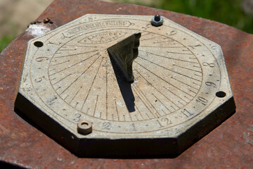 Old metal sundial with clear light showing the time in the middle of the day