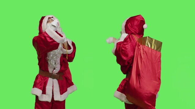 Saint nick bandmaster chief in costume accompany professional orchestra as choir musician, standing over greenscreen. Santa claus with gifts bag playing band music, musical conductor.