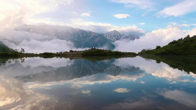 timelapse view of Happo Pond in the Hakuba valley in Japanese Alps, beautiful mountain lake with reflection of the mountains on a foggy morning, hiking in Japan