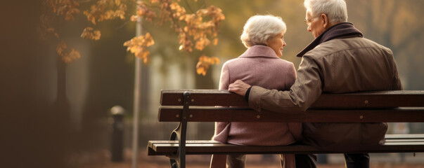 A picture of an elderly couple sitting on a park bench his arm around her shoulder both looking off sadly into the distance.