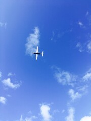 A light aircraft flying leisurely through the clouds in a peaceful clear sky