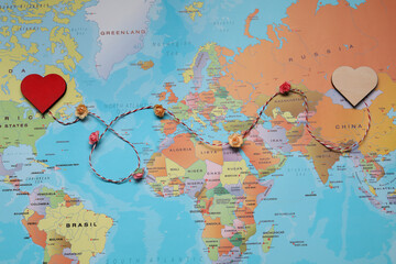 Decorative cord with hearts on world map symbolizing connection in long-distance relationship, top...