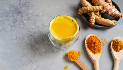 Ingredients for turmeric latte. Ground turmeric, curcuma root, cinnamon, ginger, black pepper on grey background. Spices for ayurvedic treatment. Alternative medicine concept.