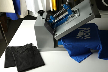 Printing logo. Heat press with blue t-shirt on white table