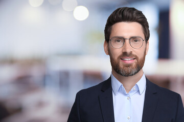 Handsome confident man with eyeglasses in office, space for text