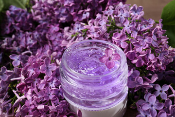 Obraz na płótnie Canvas Jar of cosmetic product and lilac flowers on table