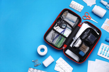 Flat lay composition with first aid kit on light blue background. Space for text