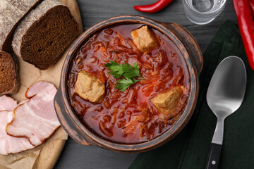 Tasty borscht in bowl served on grey wooden table, flat lay